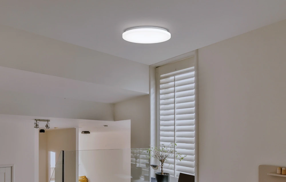 Lampă Yeelight MercuryE C260 montată în interior cu jaluzele verticale și un ghiveci pe pervaz.
