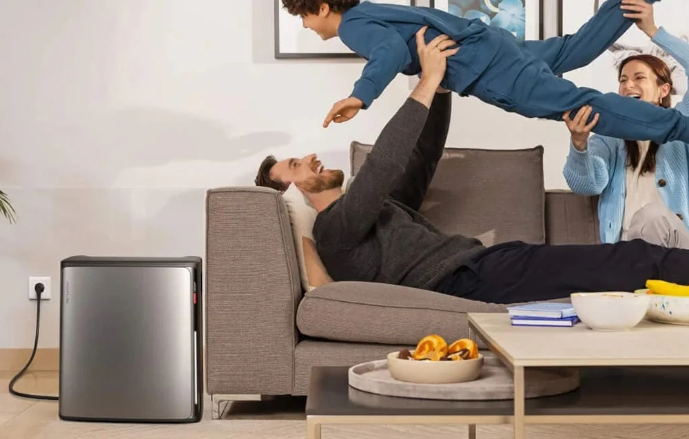 O familie se joacă în camera de zi, lângă acumulatorul de energie conectat la priza de perete