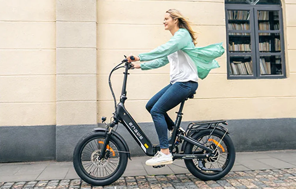 O femeie merge pe o bicicletă electrică neagră pe o stradă din oraș