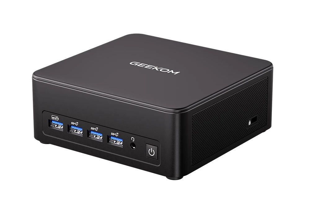 Mini PC-ul GEEKOM prezentat dintr-un unghi, afișând panoul frontal cu porturi USB, o mufă audio și un buton de pornire.