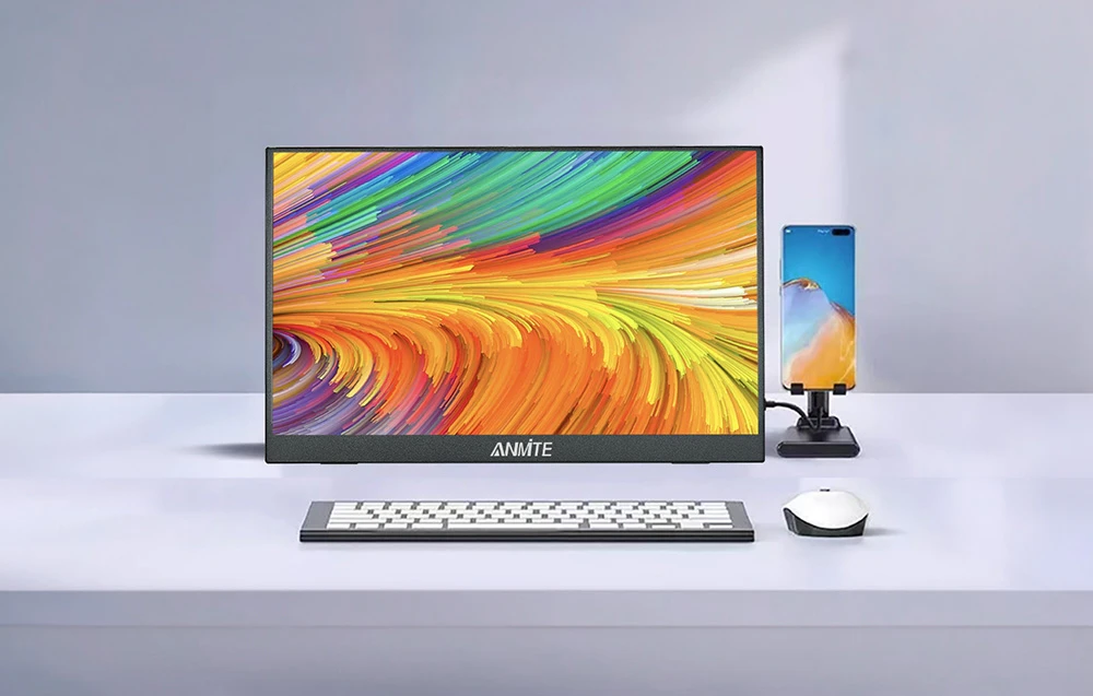 Un monitor care afișează imagini colorate pe un birou alb, cu un smartphone, o tastatură și un mouse de computer lângă el.