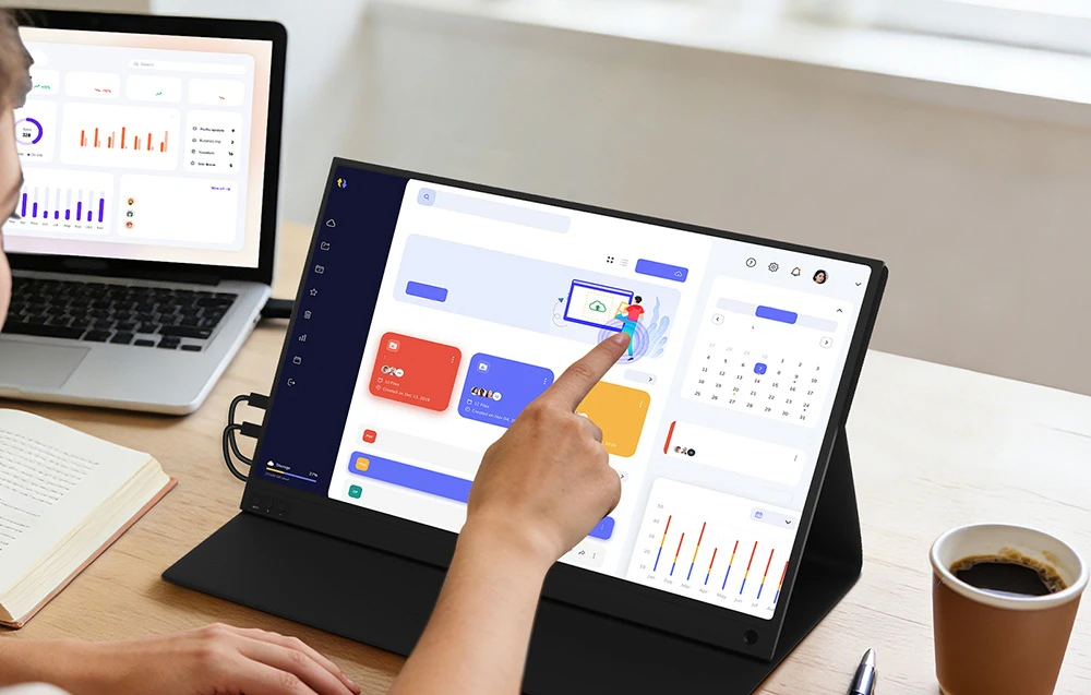 Monitor portabil folosit ca ecran secundar pentru un laptop, utilizat de o persoană care lucrează cu grafice la un birou