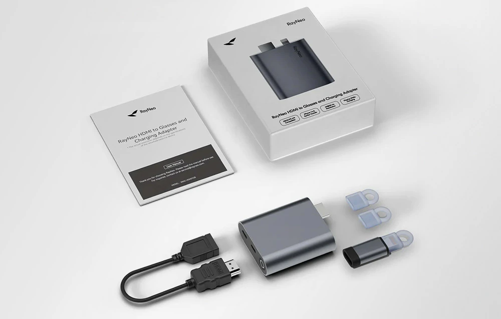 Set RayNeo cu adaptor, adaptoare, cablu HDMI și instrucțiuni, aranjate lângă ambalaj pe un fundal luminos.