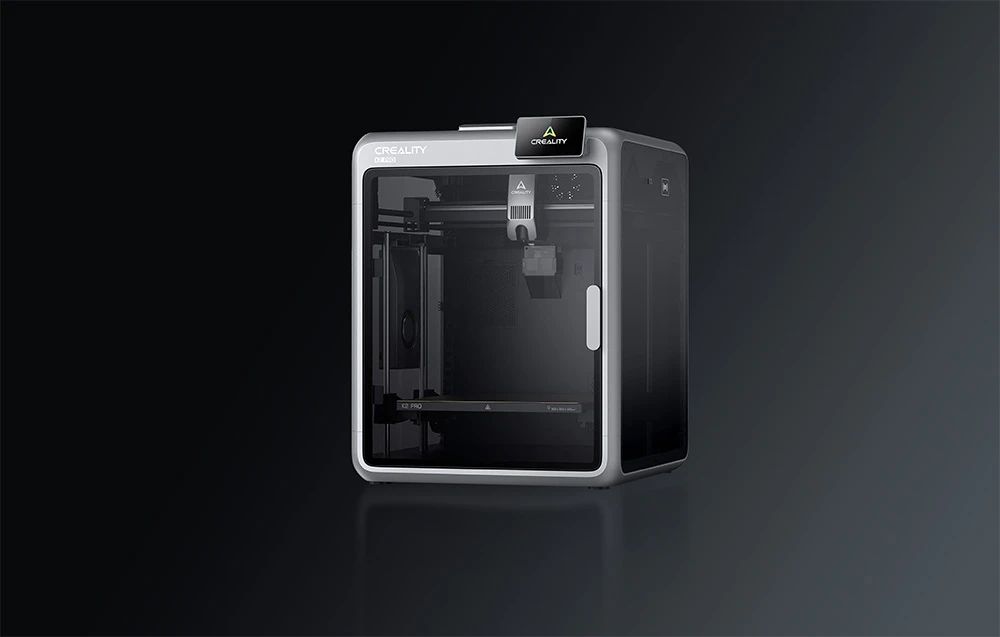 Imprimantă 3D Creality argintie și neagră cu pereți transparenți pe un fundal întunecat