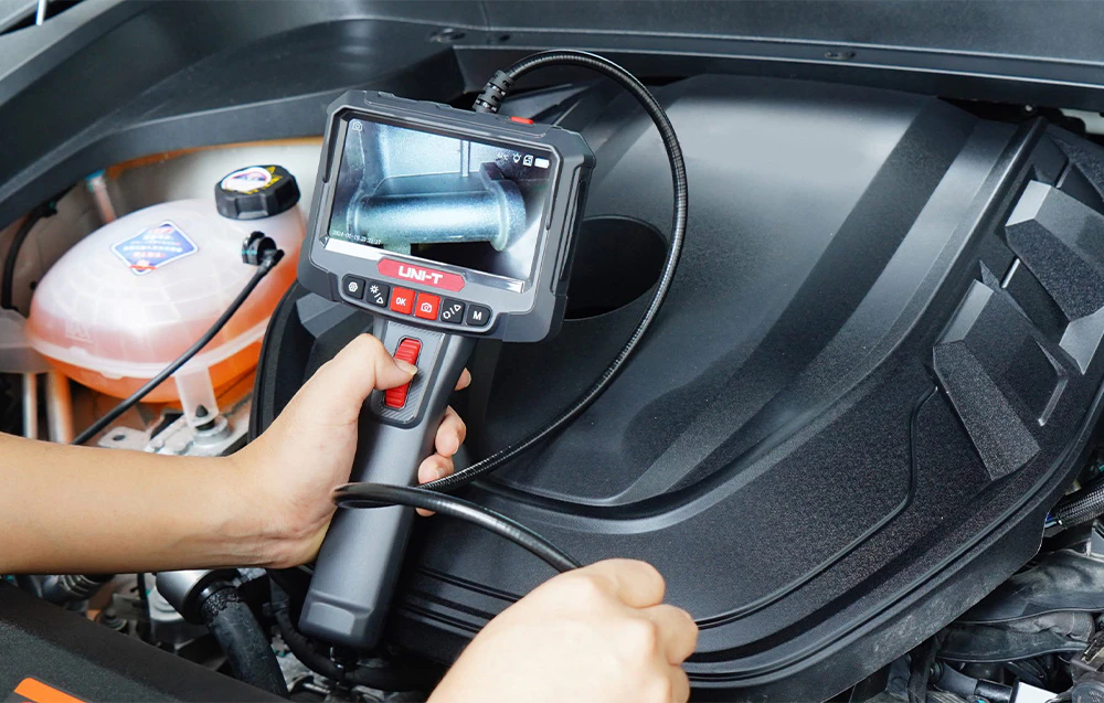 Un videoboroscop cu ecran și sondă flexibilă utilizat pentru inspectarea interiorului compartimentului motor al unei mașini.