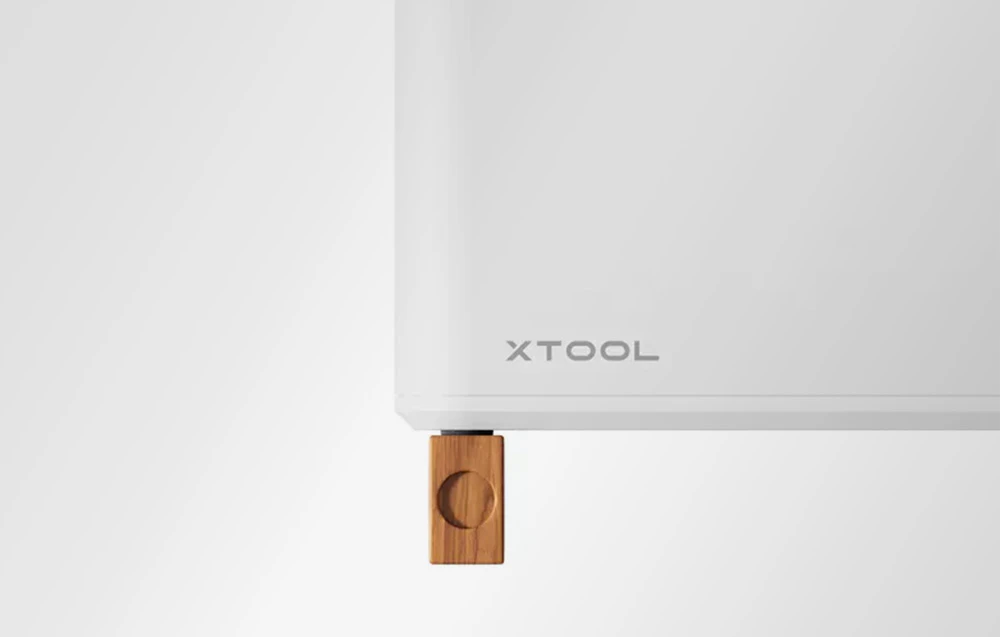 Dispozitiv xTool alb pe un suport din lemn