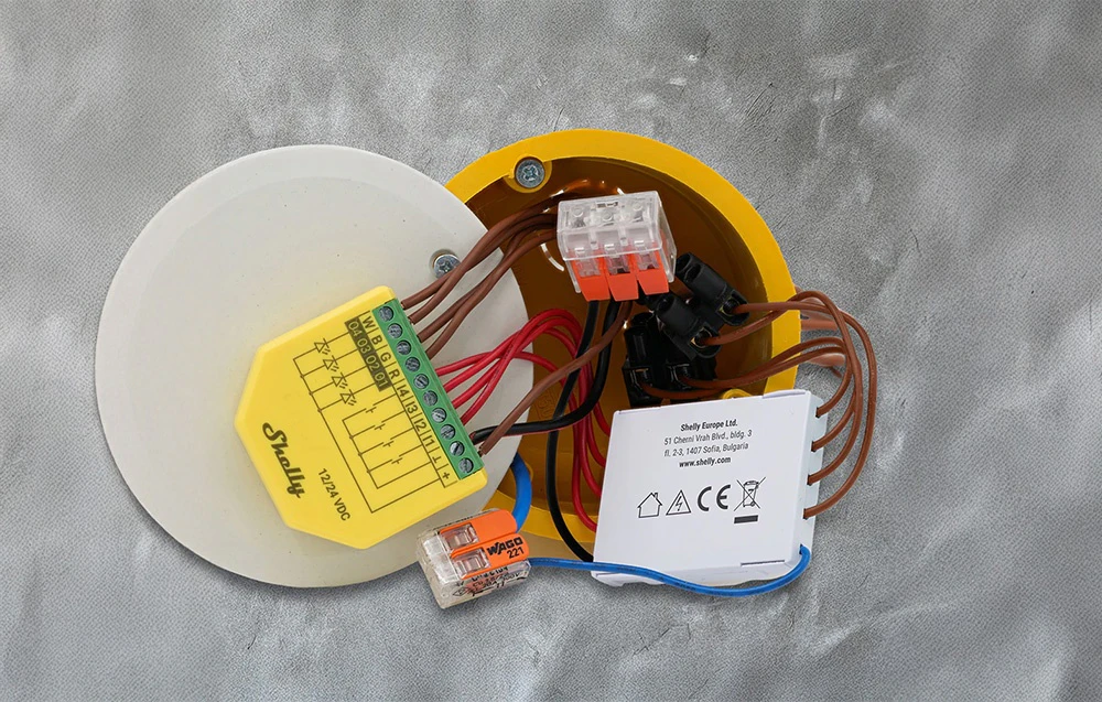 Aparat Shelly cu mai multe fire conectate în cutia electrică - conectori WAGO vizibili și modul cu carcasă galbenă