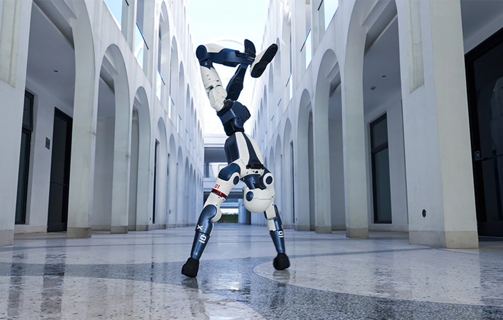 Un robot umanoid alb și albastru care face o stând pe mâini într-un coridor al clădirii
