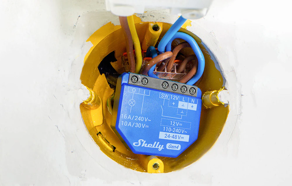 Vedere a interiorului cutiei electrice cu controlerul instalat, fire colorate și blocuri de borne.