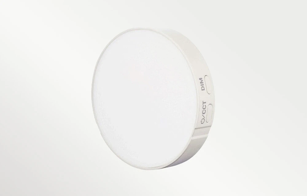 O lampă LED Godox rotundă, albă, cu butoane de control DIM și CCT vizibile pe partea laterală a carcasei
