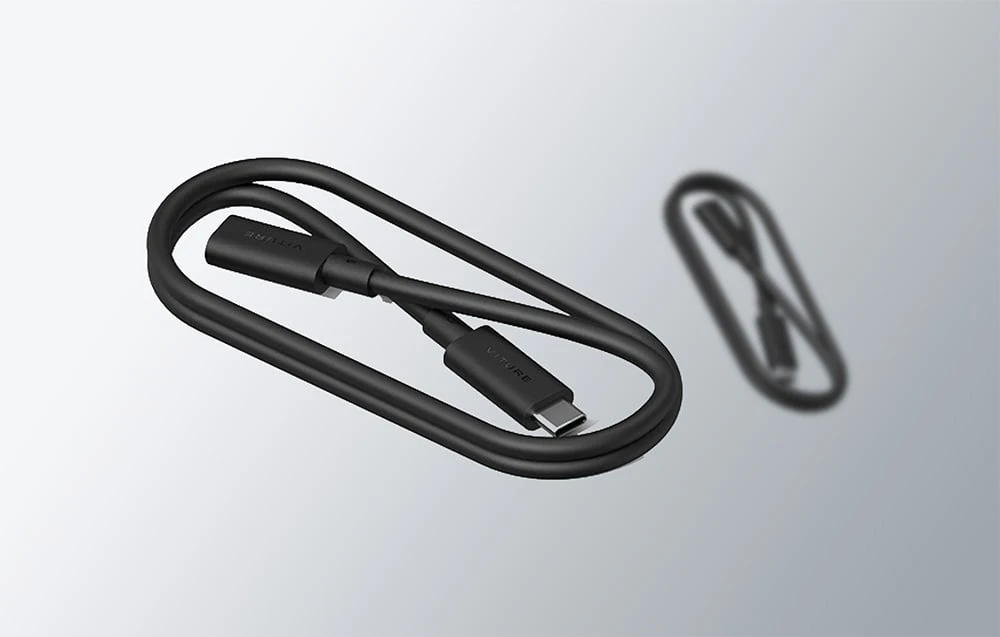 Un cablu USB-C negru spiralat de la VITURE se află lângă reflexia sa neclară pe un fundal deschis