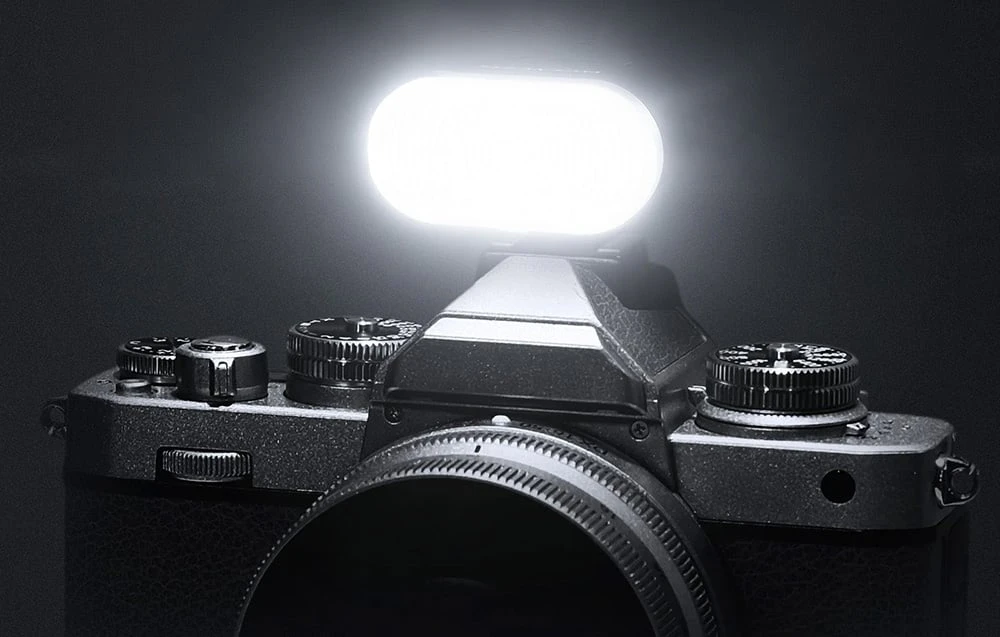 O fotografie alb-negru a unui bliț mic, dreptunghiular, care emite o lumină puternică pe un aparat foto.