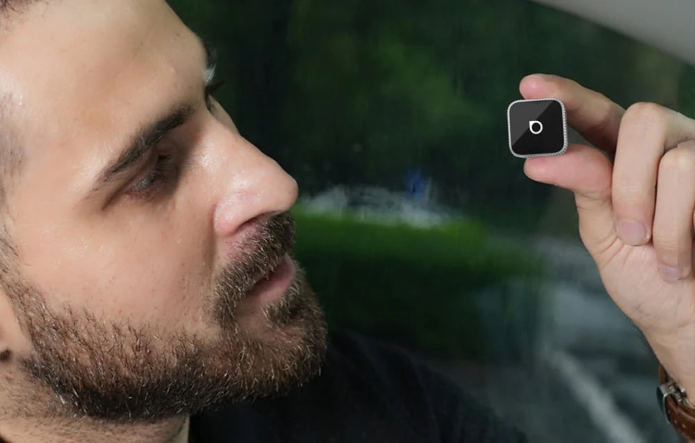 Un bărbat se uită la un adaptor Ottocast mic ținut în mână