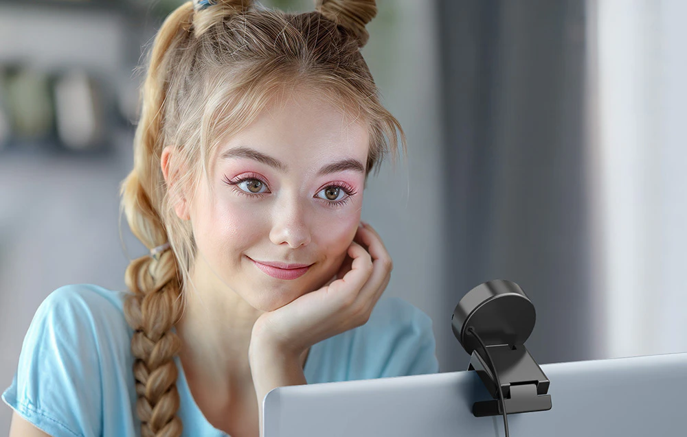 O tânără privește spre camera montată pe marginea unui laptop în timpul unui apel video.