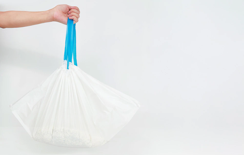 Mână ținând un sac alb cu un șnur albastru