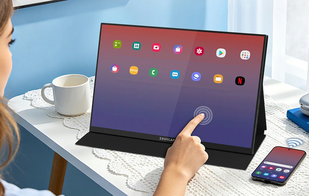 O femeie atinge ecranul unui monitor portabil ZEUSLAP conectat wireless la un smartphone aflat pe un birou