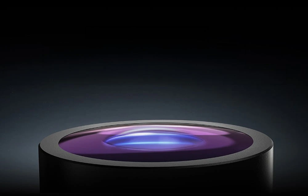 Un prim-plan al unei lentile optice rotunde, din sticlă, cu o reflexie a luminii de culoare albastru-violet