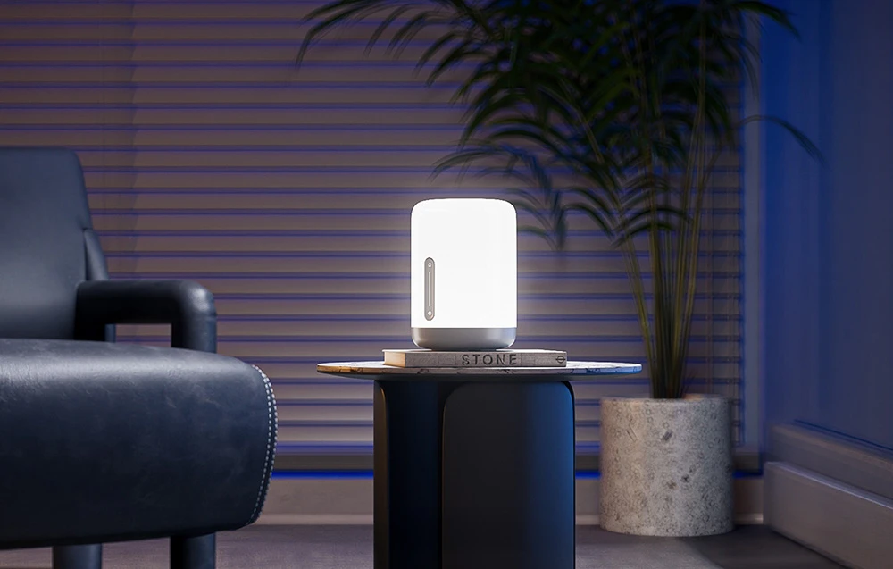 O lampă care emite o lumină puternică pe o măsuță dintr-un living modern, cu o plantă în ghiveci în fundal