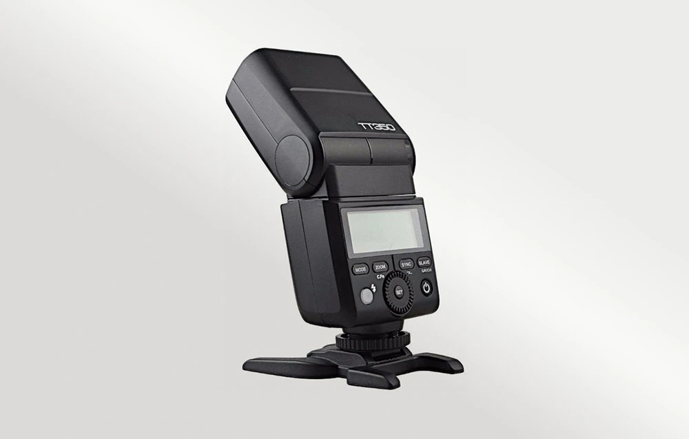 Blițul Godox TT350 negru pe un stativ negru, vedere laterală din spate, ecranul LCD oprit și capul înclinat înapoi