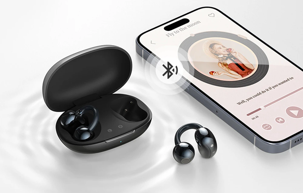 Căști wireless negre și carcasă de încărcare lângă un smartphone cu aplicație de muzică