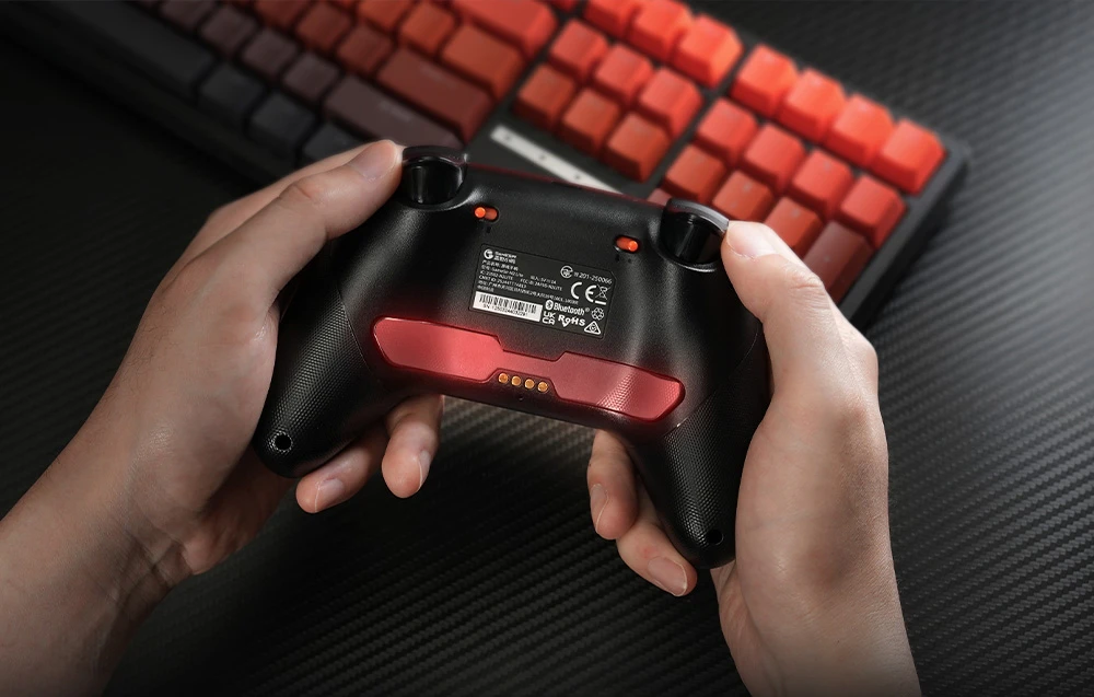 Vedere din spate a controlerului GameSir ținut în mână, cu eticheta și inserția roșie vizibile.
