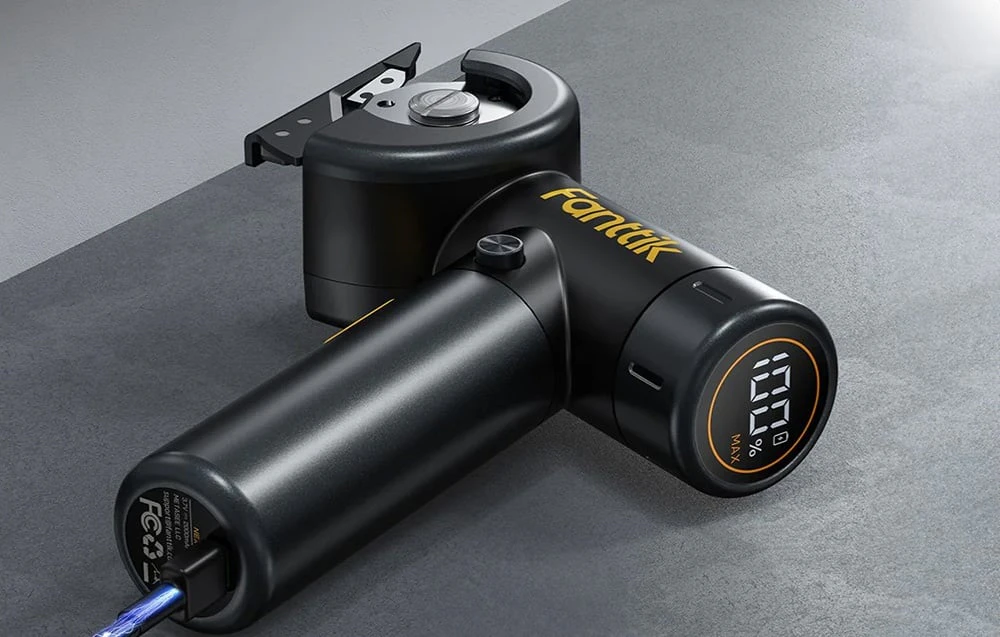 Un cutter electric Fanttik negru se află pe un blat gri conectat la un cablu USB.