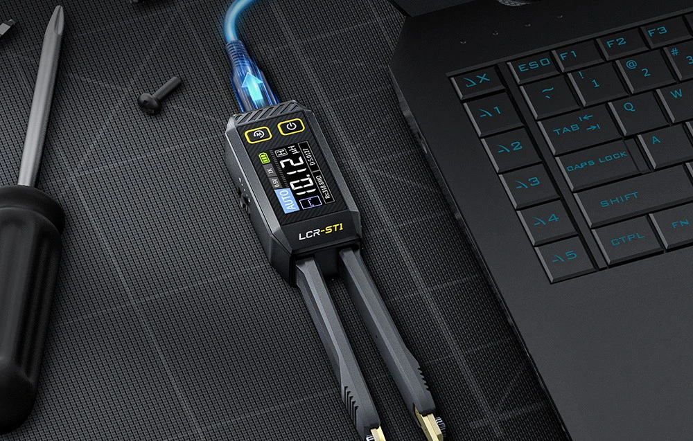 Pensetă electronică de măsurare conectată la un laptop stă pe o mată neagră lângă o șurubelniță și șuruburi.