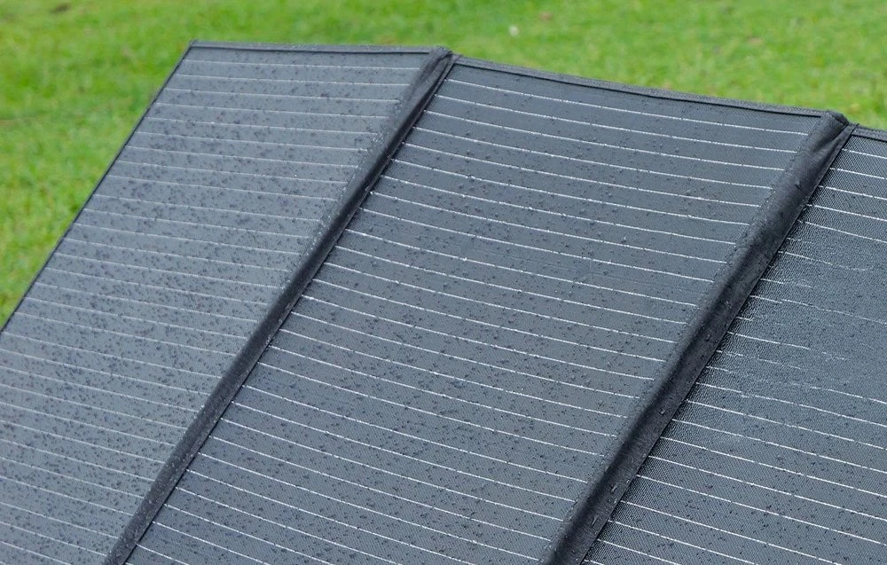 Un prim-plan al suprafeței panoului solar pliabil Fossibot acoperit cu picături de apă