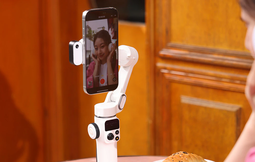 Un smartphone montat pe un gimbal în timp ce înregistrează un videoclip în interior, cu o previzualizare vizibilă pe ecran.