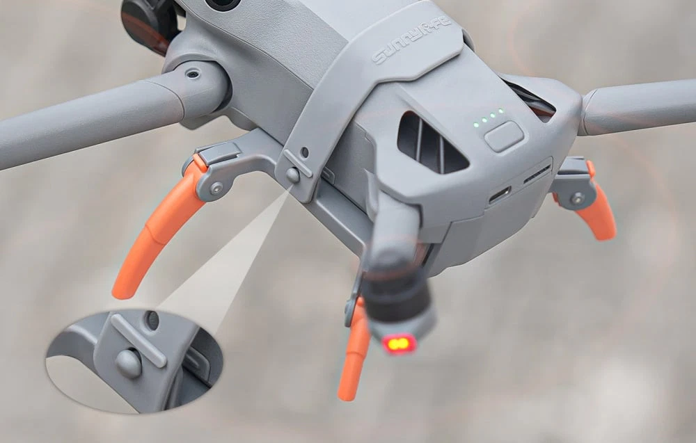 O vedere aeriană a părții din spate a dronei DJI Mini 5 Pro cu picioarele portocalii instalate și un zoom close-up al mecanismului de fixare