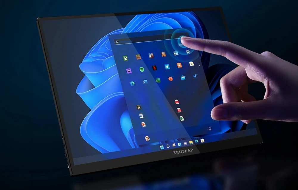 O mână atinge ecranul tactil al monitorului ZEUSLAP care afișează desktopul Windows