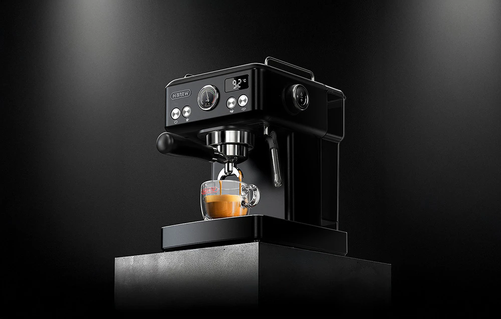 Cafetieră cu piston HiBREW neagră pe un fundal întunecat, care arată panoul de control iluminat, afișajul temperaturii și procesul de preparare a espresso-ului într-o ceașcă de sticlă.