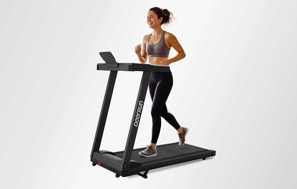O femeie zâmbitoare, îmbrăcată în ținută sportivă, aleargă pe o bandă de alergare modernă, neagră, marca DeerRun.