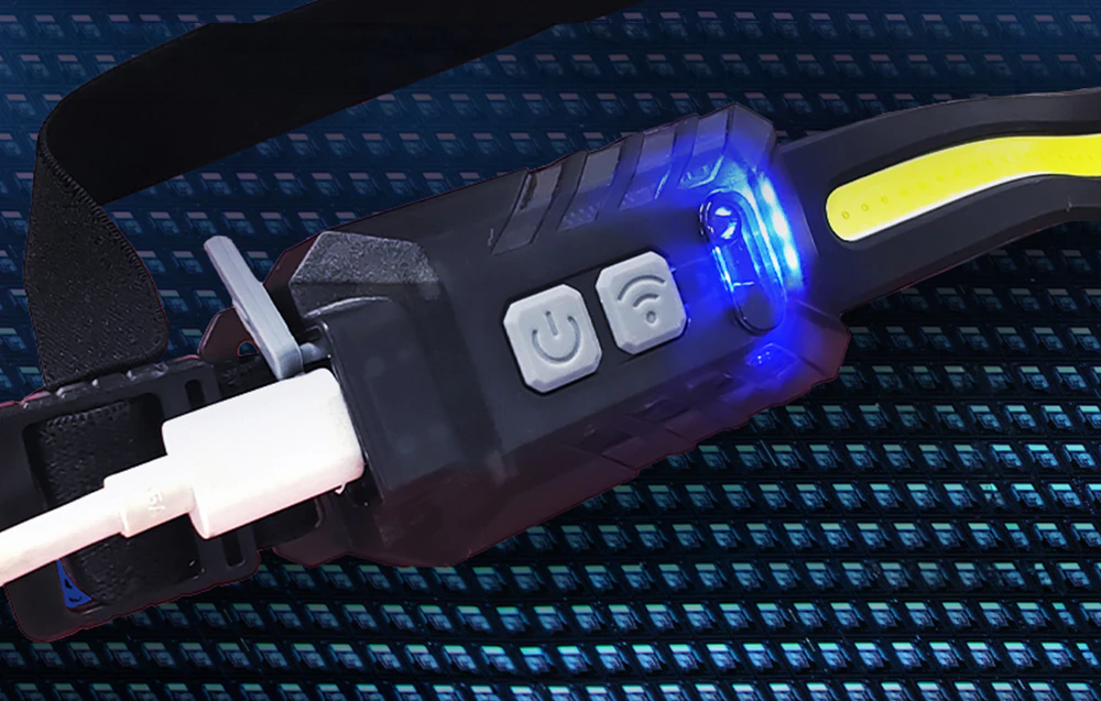 Detaliu al panoului de control al lanternei frontale cu butoane și un cablu de încărcare USB alb conectat.