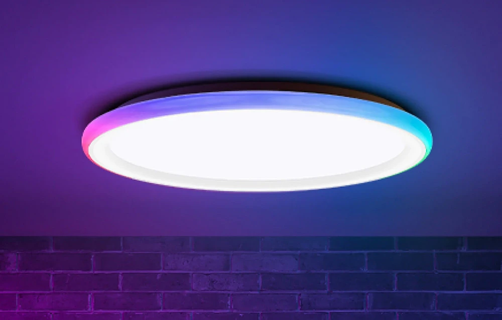 Plafonieră Yeelight Mars C300 care emite lumină albă și colorată pe un perete de cărămidă.