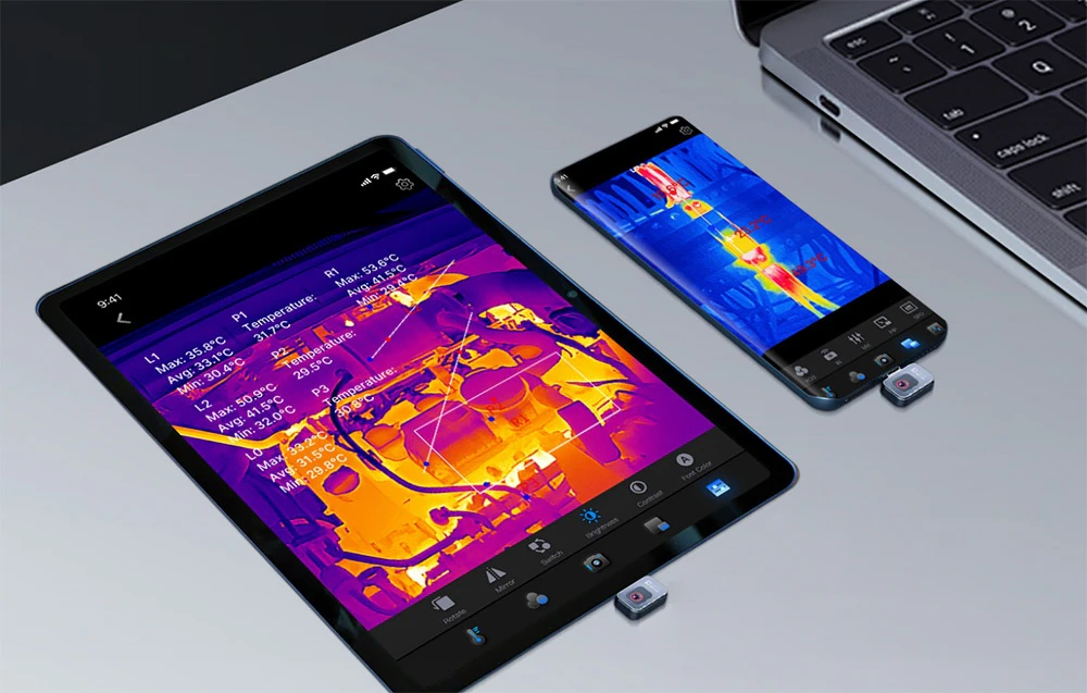 O tabletă și un smartphone, ambele cu mini-camere termice și imagini termice, se află pe o masă lângă un laptop
