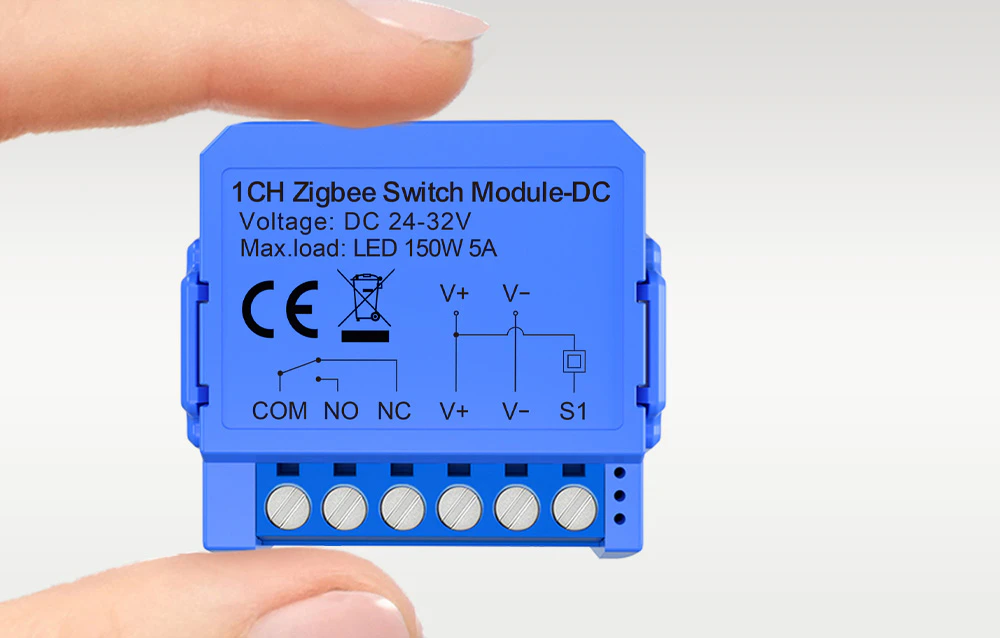 Mâini ținând un modul de comutare Zigbee compact, de culoare albastră, cu conectori vizibili și un certificat CE