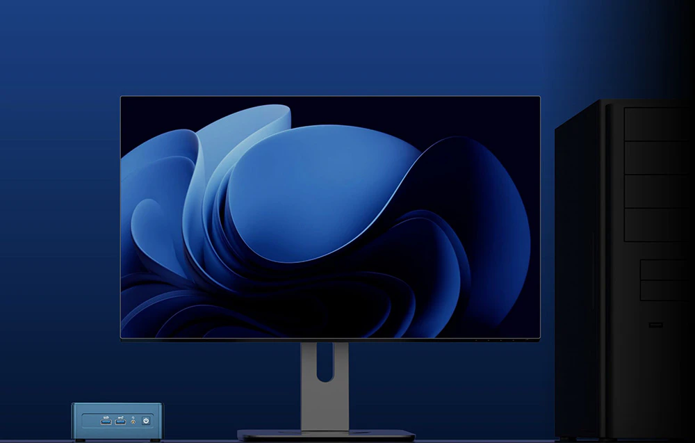 Monitor care afișează imaginea de fundal Windows lângă un mini PC mic și o carcasă mare de tip turn neagră