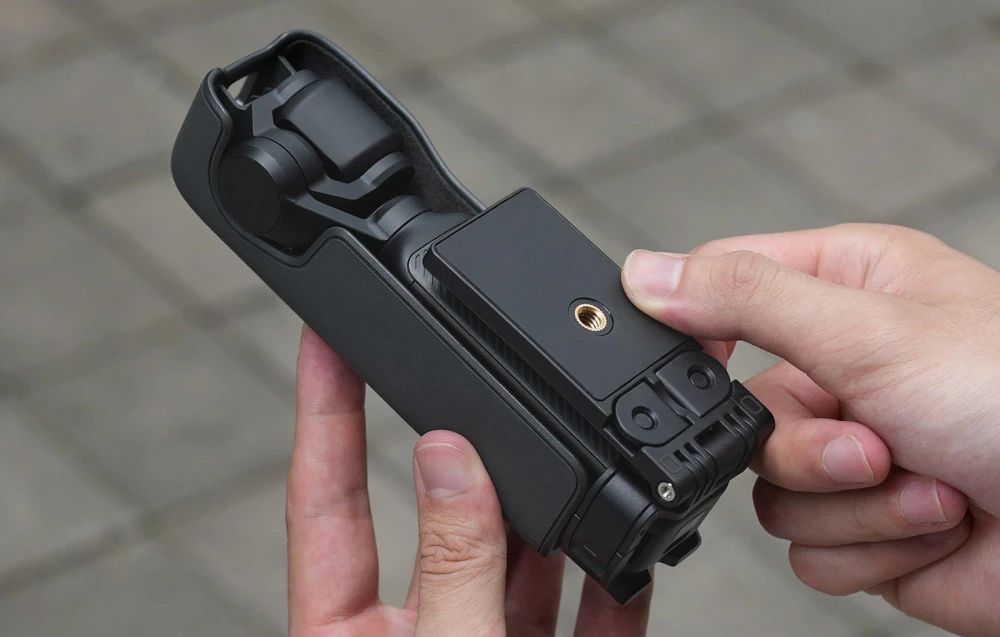 O persoană ține în mână o cameră DJI Pocket pliată cu suportul magnetic cu filet instalat