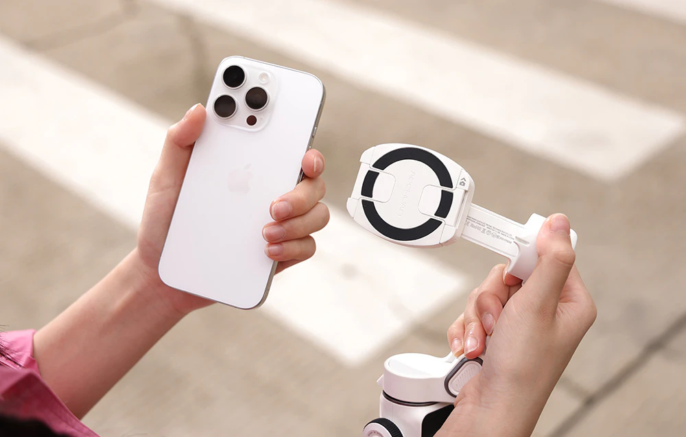 O mână ține un iPhone și un suport magnetic atașat la gimbal, gata de conectare.