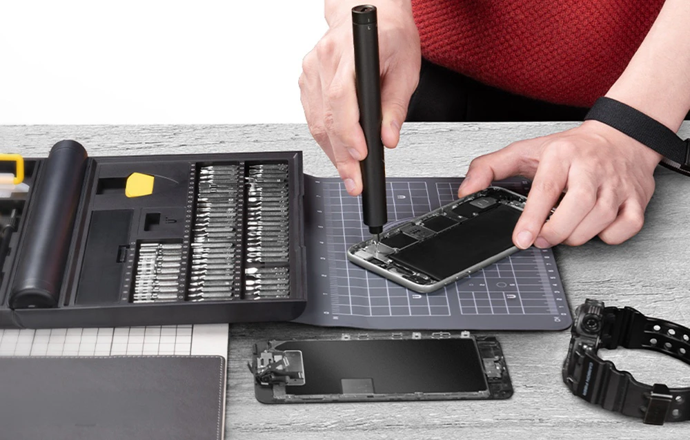 Demontarea unui smartphone cu ajutorul unei șurubelnițe electrice într-un atelier de service dotat cu accesorii.