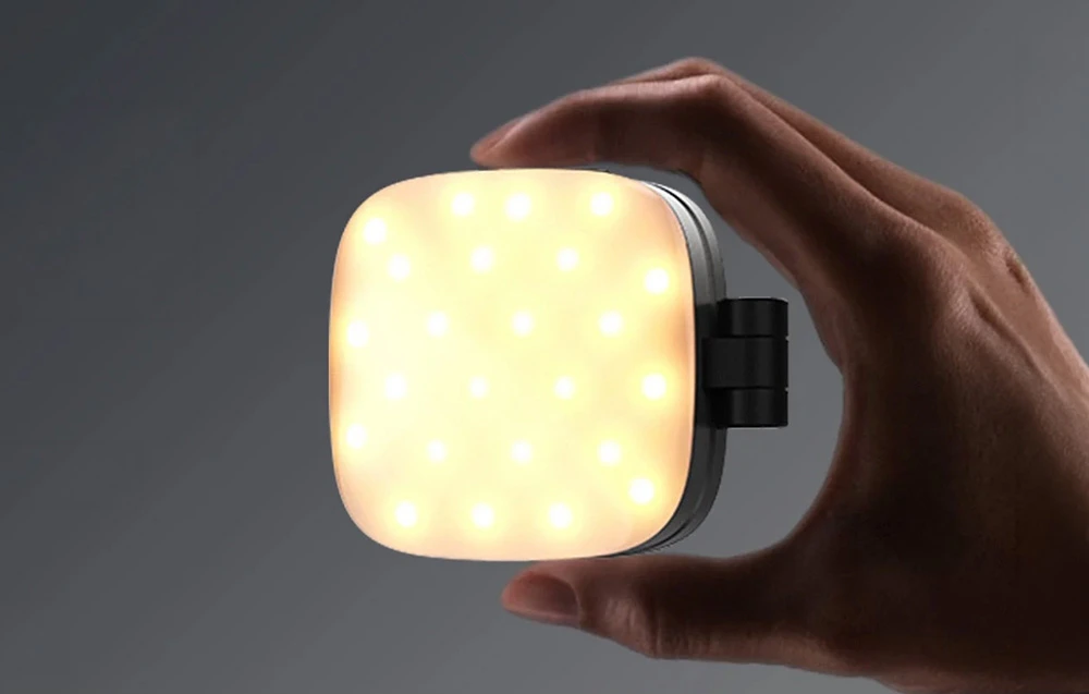 O mână care ține o lampă mică, pătrată, pentru selfie-uri de la Neewer, cu LED-uri luminoase.