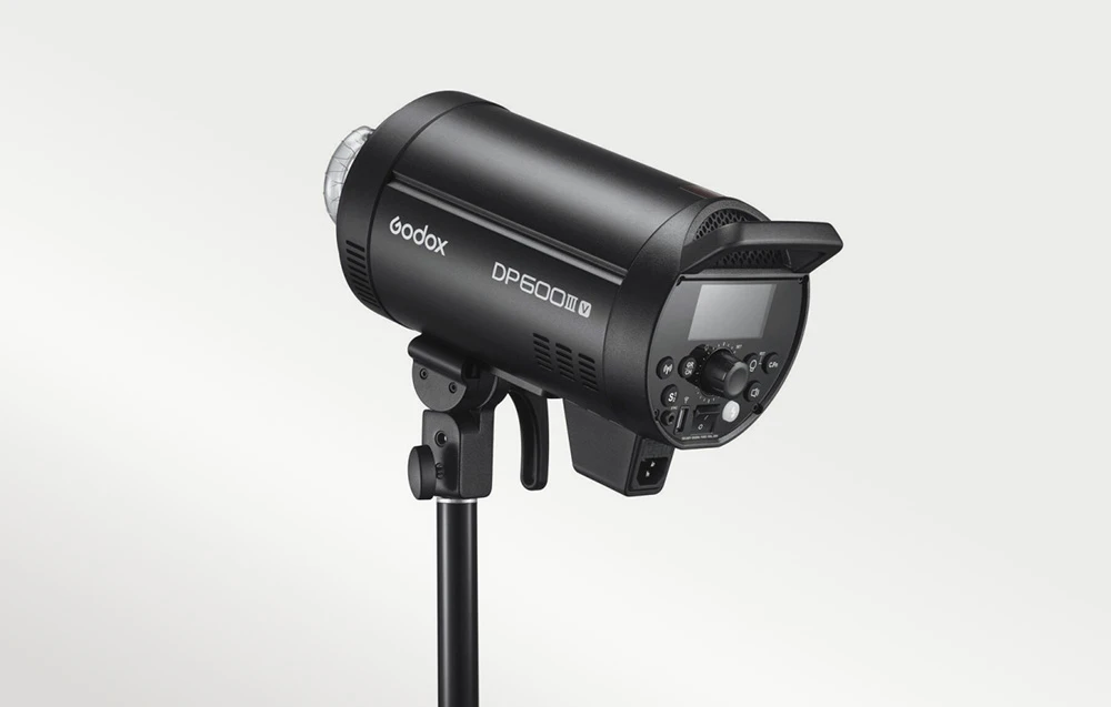 Blițul de studio Godox DP600III-V montat pe un trepied, vedere laterală a carcasei negre și a panoului de control