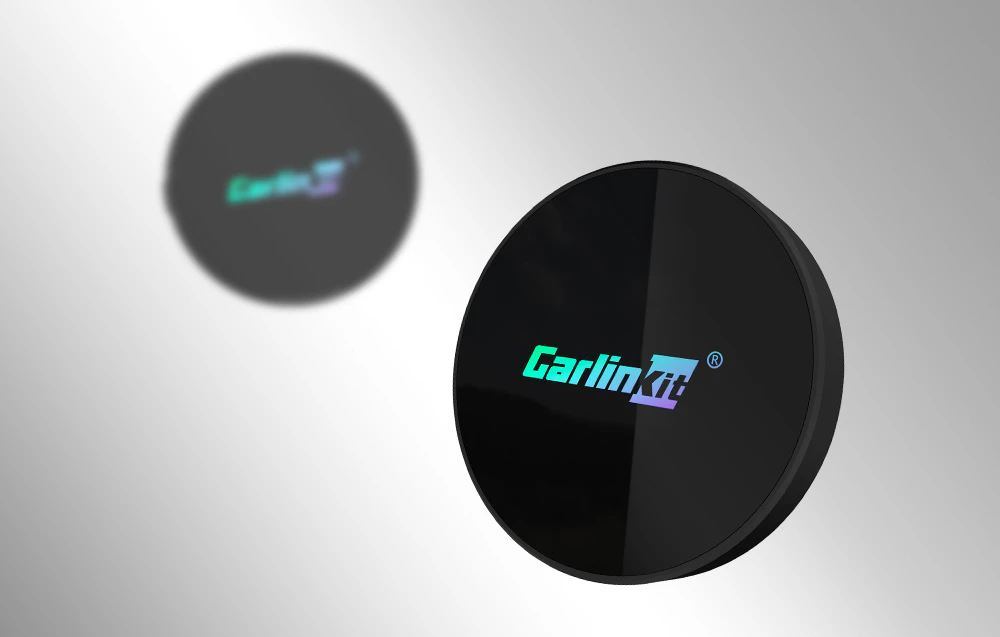 Două adaptoare wireless Carlinkit, unul clar în prim-plan, celălalt estompat în fundal.
