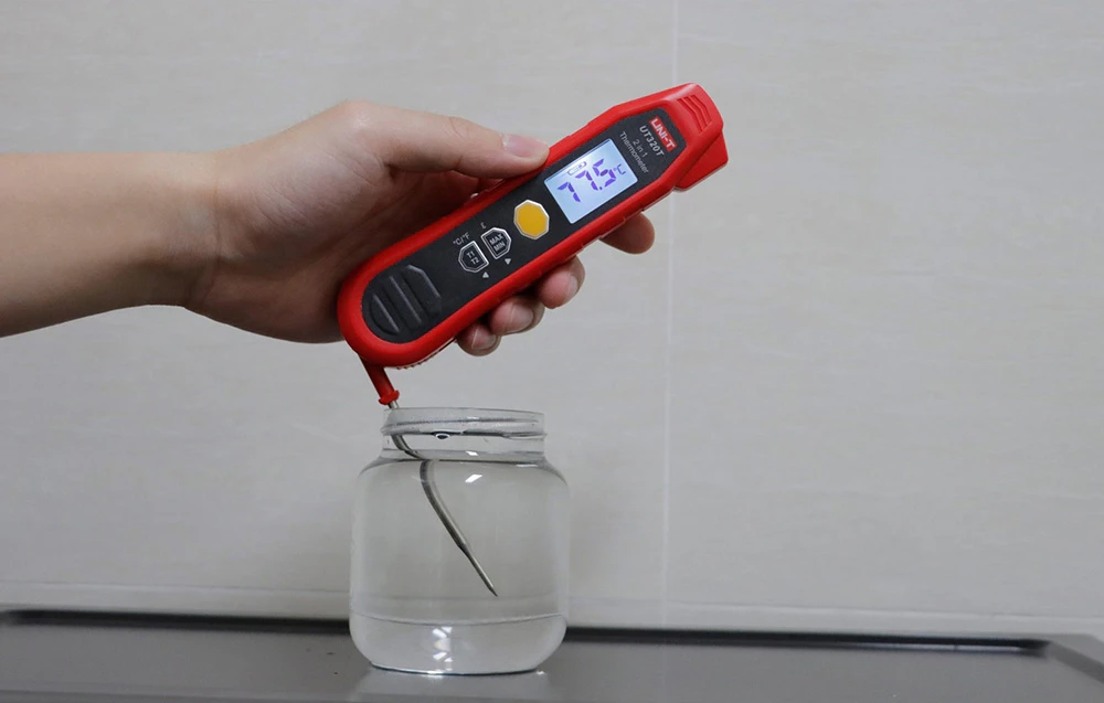 Termometru electronic cu sonda scufundată într-un borcan cu lichid, măsurând temperatura lichidului