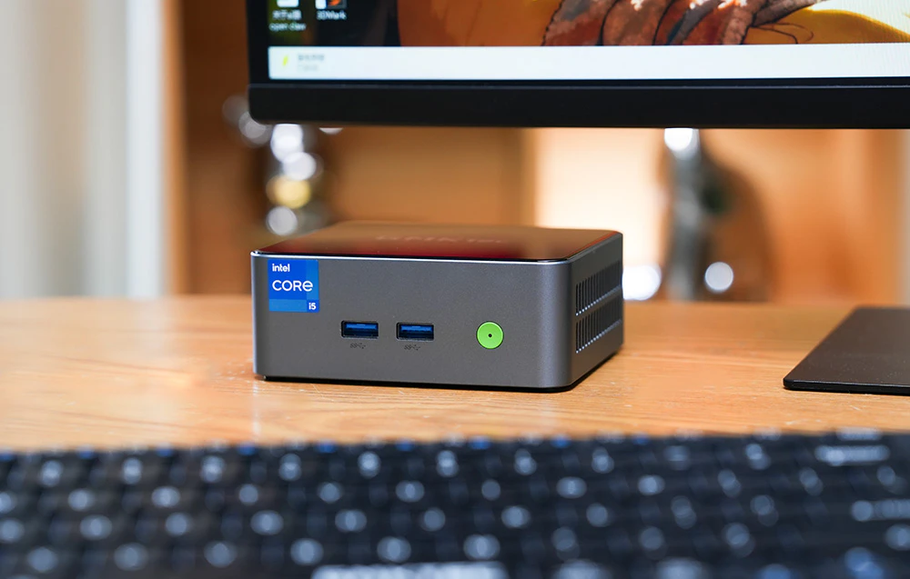 Mini PC-ul GMKtec M3 Pro așezat pe un birou sub un monitor, gata pentru munca zilnică și divertisment.
