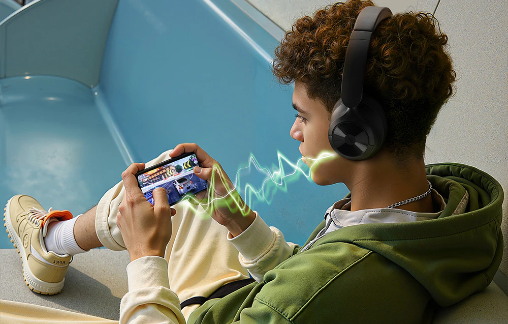 Un băiat purtând căști care joacă un joc pe smartphone-ul său, cu o vizualizare grafică a latenței audio reduse