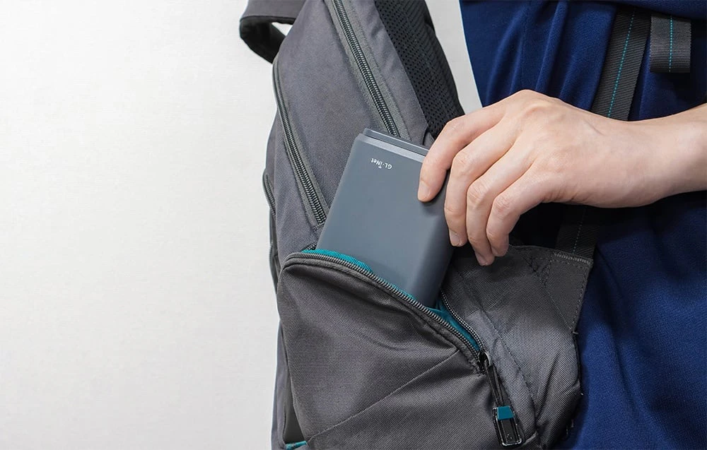 Un router GL.iNet introdus într-un rucsac gri