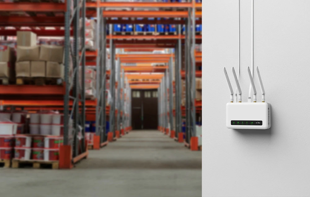 Un router alb montat vertical pe un perete în interiorul unui depozit logistic cu rafturi înalte pentru paleți.